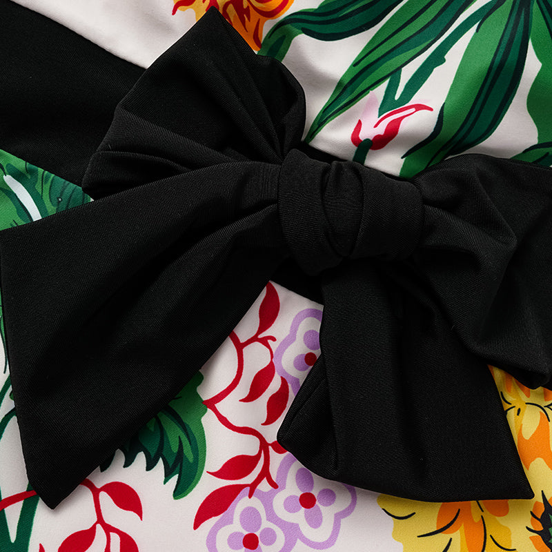 One-piece swimsuit with dropped shoulder straps, tie back, color block print and skirt